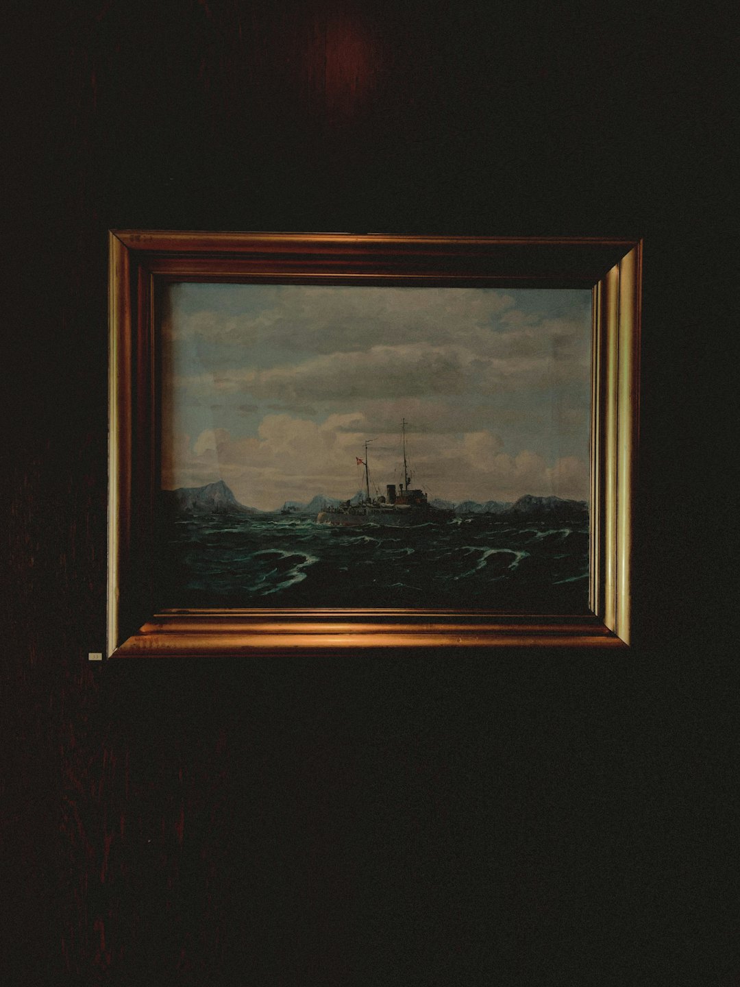 Un quadro di una nave in mare mosso appeso a una parete.