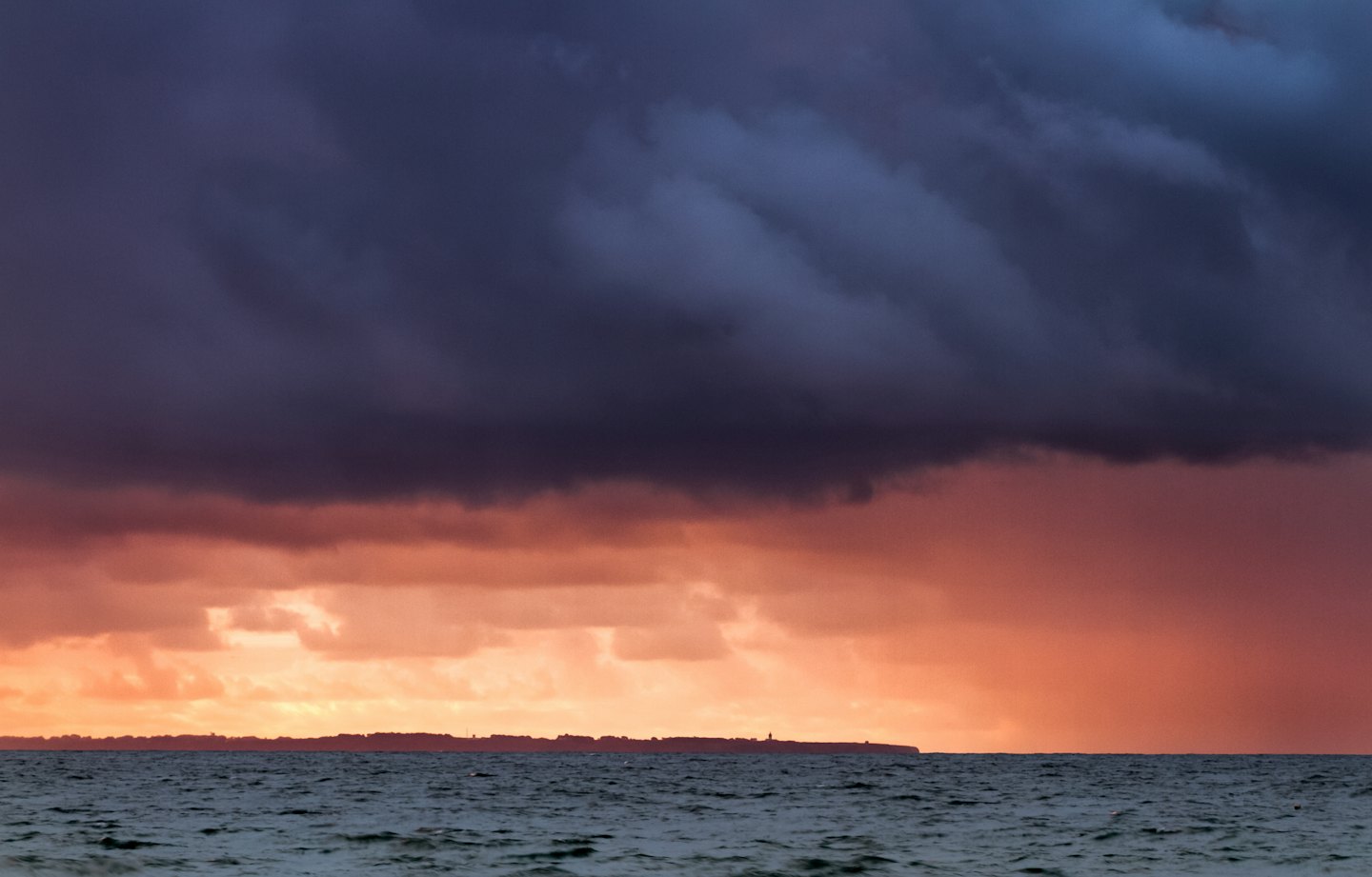 Nuvole tempestose incombono sull'oceano al tramonto.