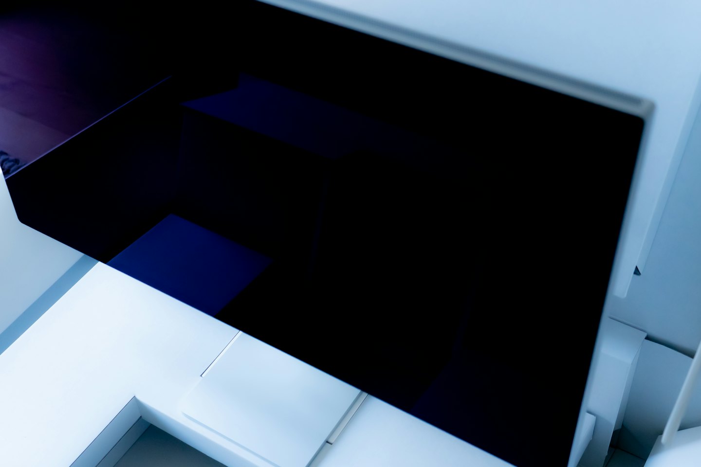 Forme architettoniche geometriche bianche e blu si intersecano con vetro scuro.